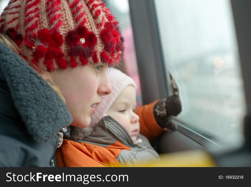 Young mother with daughter look to window riding by bus. Young mother with daughter look to window riding by bus