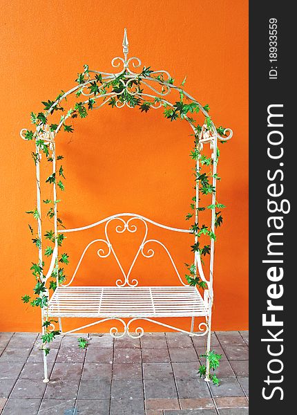 White romantic vintage chair with plant and orange wall. White romantic vintage chair with plant and orange wall