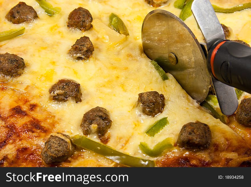 Picture of Closeup of meatball pizza with pizza wheel. Picture of Closeup of meatball pizza with pizza wheel