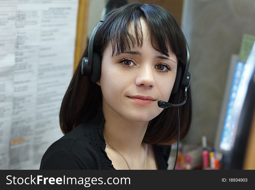 Beautiful young girl smiling brunette phone operator in headphones. Beautiful young girl smiling brunette phone operator in headphones