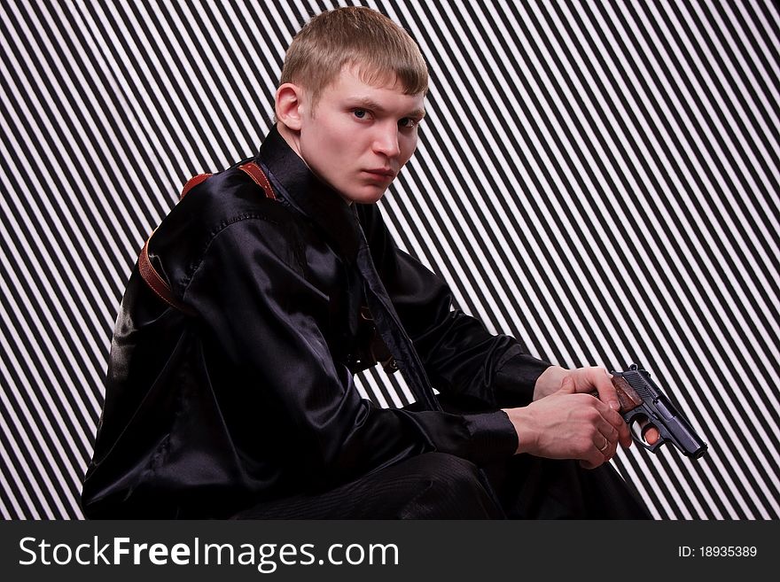 Serious man with a gun against striped background