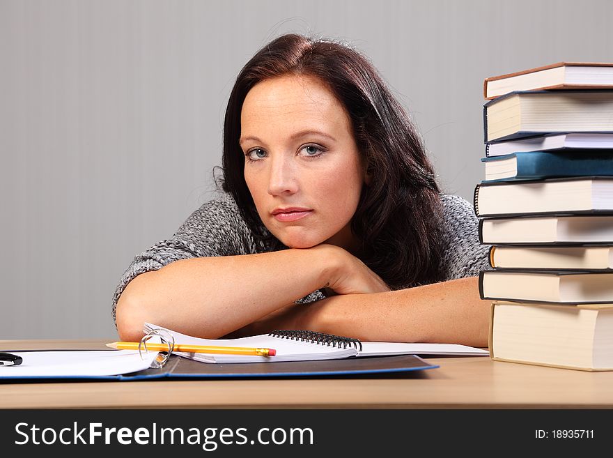 Tired from homework woman rests chin on desk