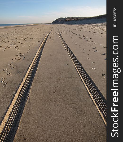 This is a photo of  an ocean beach with tire tracks in the sand. This is a photo of  an ocean beach with tire tracks in the sand.