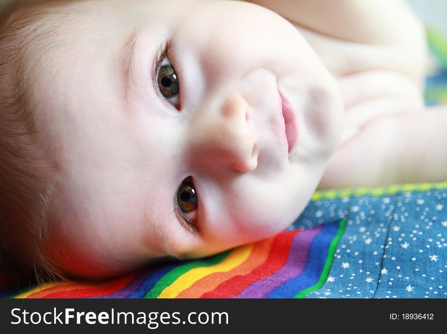 6 month old baby staring right into the camera laying on his handmade blanket.