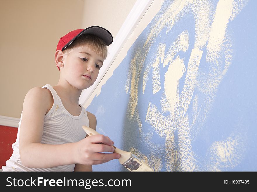 Young boy painting a blue wall with yellowish paint. Young boy painting a blue wall with yellowish paint.