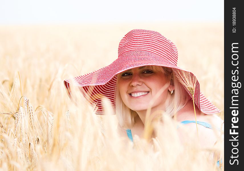 Beautiful woman with hat in wheat meadow on sunny day