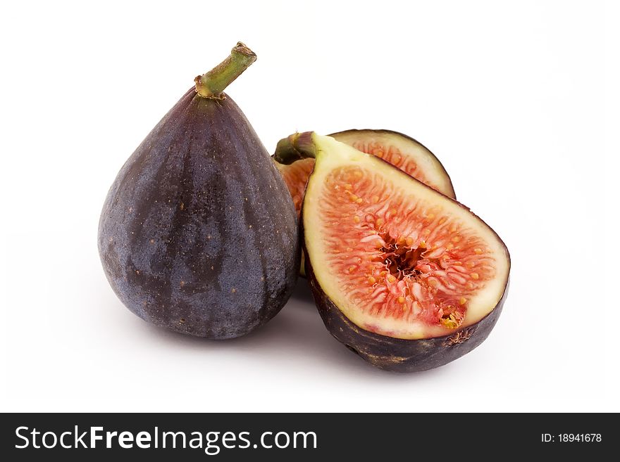 One whole fig and one cut in half an a white background. One whole fig and one cut in half an a white background