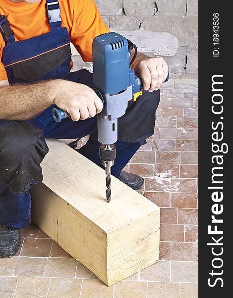 A man drilling a hole in wooden block. A man drilling a hole in wooden block