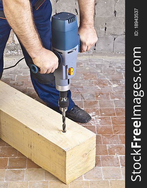 A man drilling a hole in wooden block. A man drilling a hole in wooden block