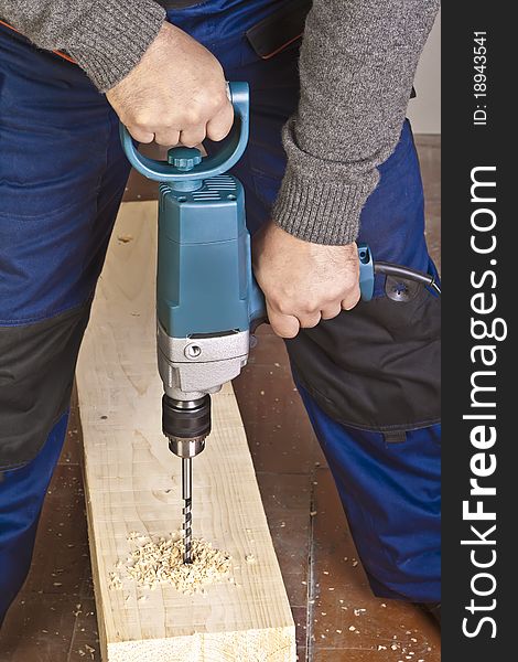 A man drilling a hole in wooden block. A man drilling a hole in wooden block