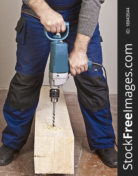 A man drilling a hole in wooden block. A man drilling a hole in wooden block