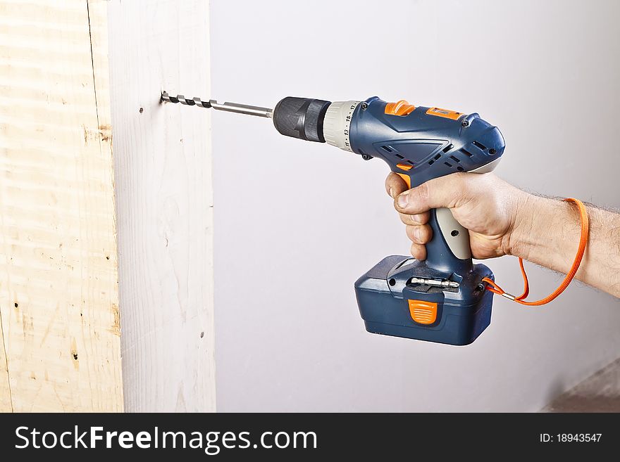 A man drilling a hole in wooden block. A man drilling a hole in wooden block