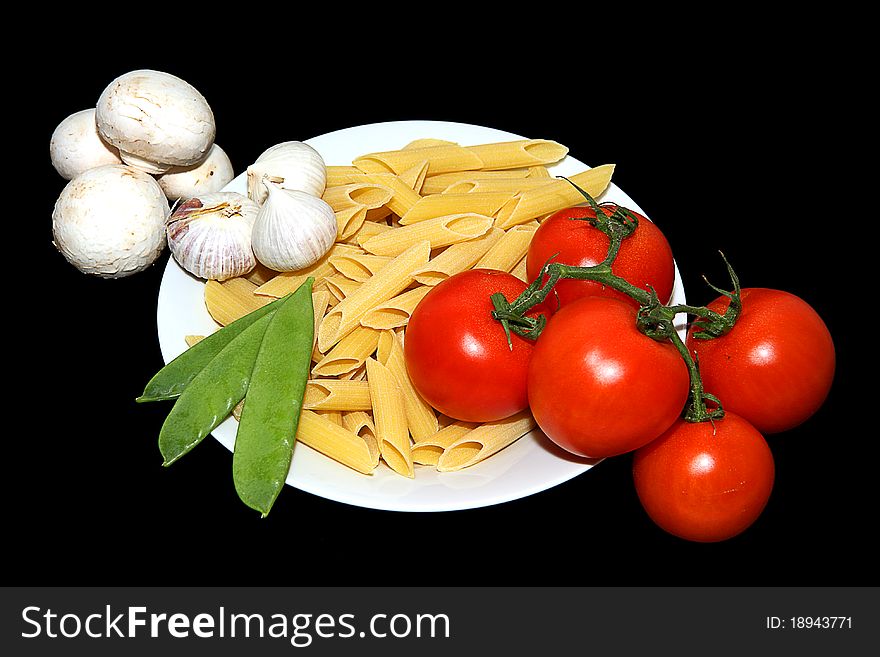 A white plate with pasta tomato garlic and mange tout arranged. A white plate with pasta tomato garlic and mange tout arranged