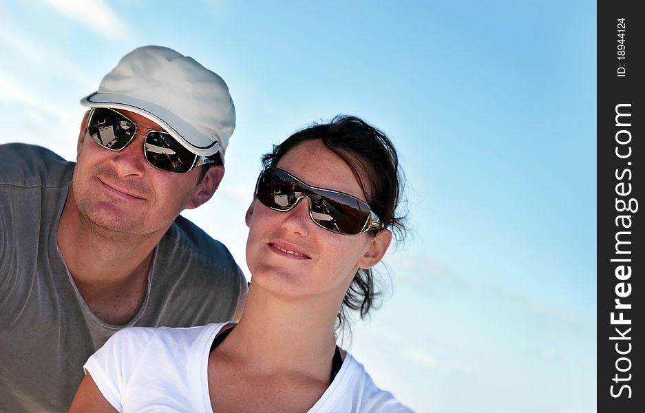 Closeup of a happy young couple on summer vacation, suntanned and wearing sunglasses. Closeup of a happy young couple on summer vacation, suntanned and wearing sunglasses.