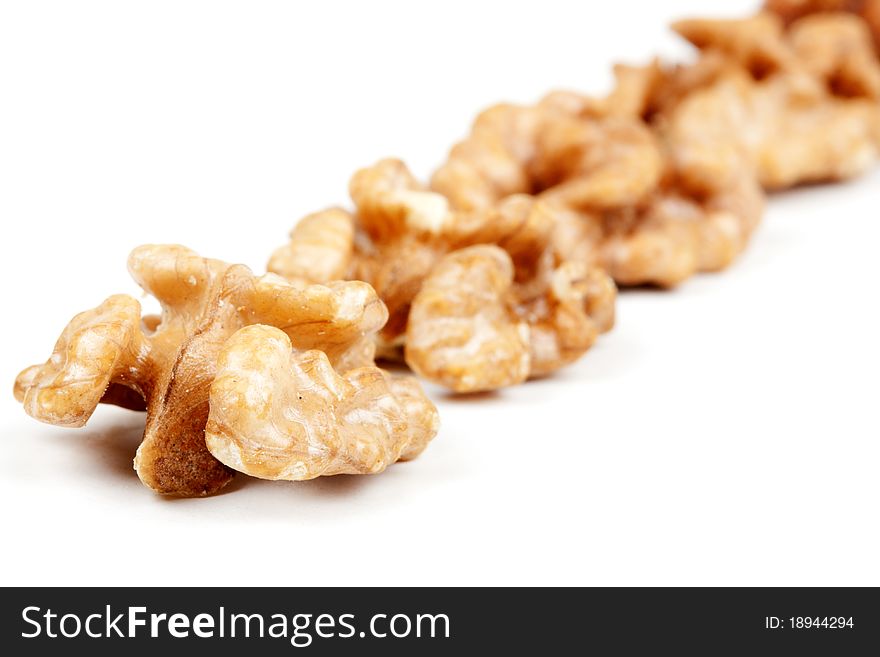 Halves peeled walnuts arranged in a line on a white background