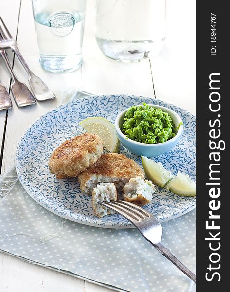 Fish patties with peas purée and lemon on blue plate and rustic wooden table. Fish patties with peas purée and lemon on blue plate and rustic wooden table