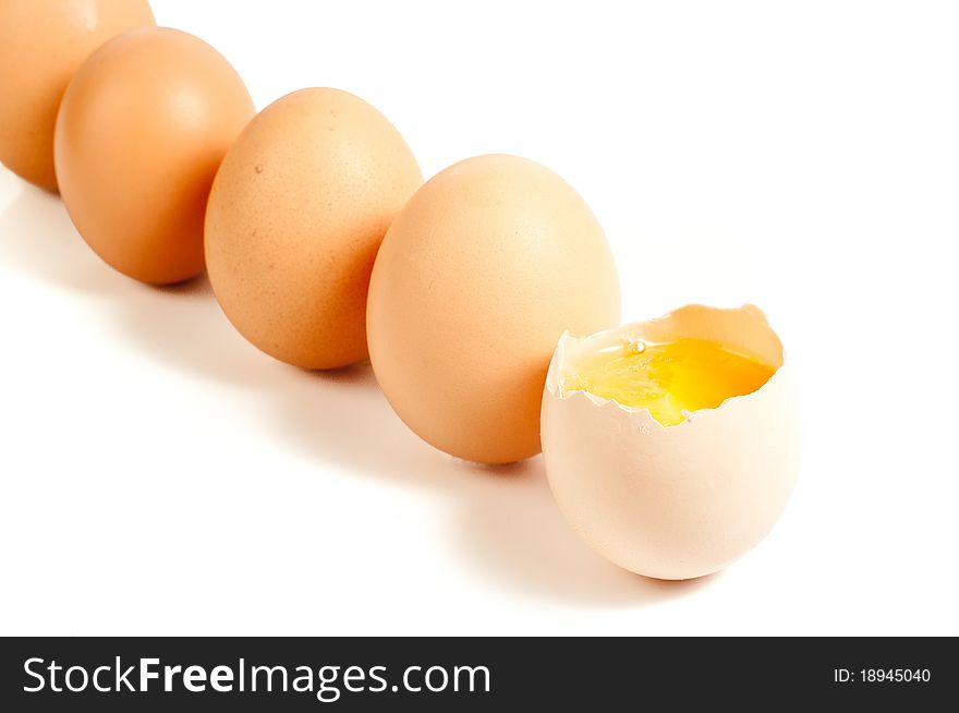 Five eggs standing, one cracked On white background