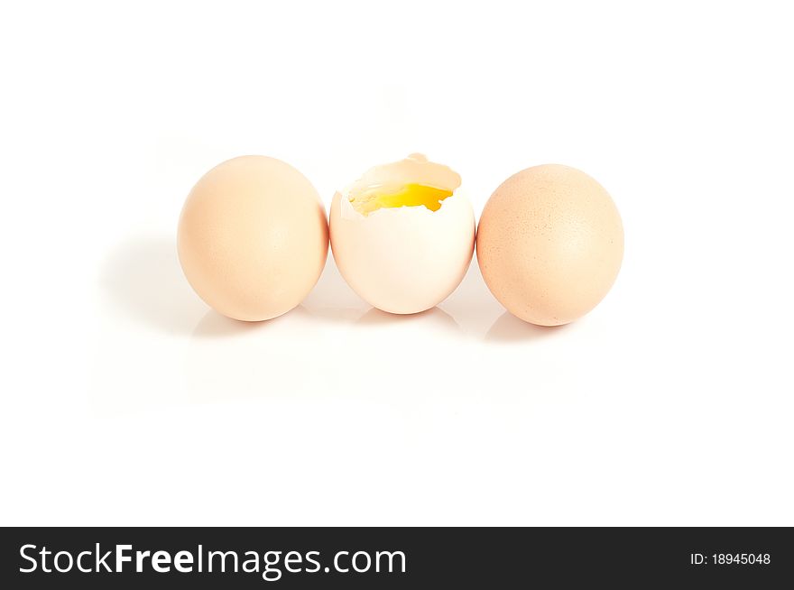 Three eggs standing, one cracked On white background