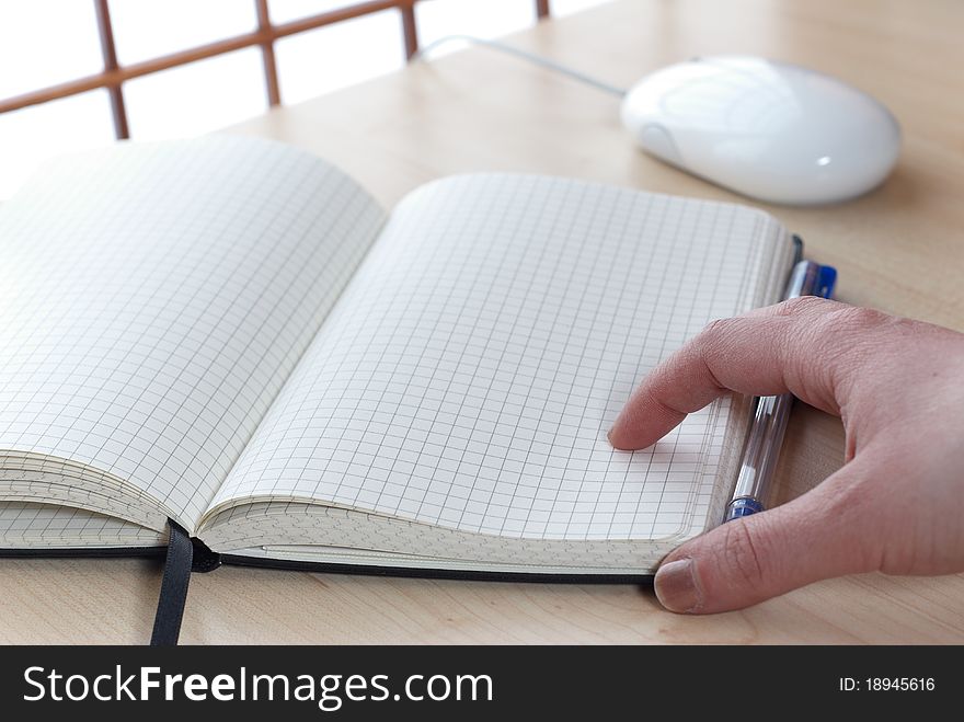 Notebook at a desk with a hand