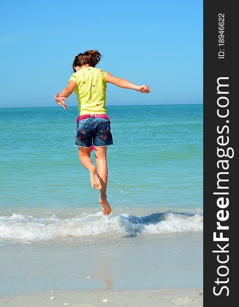 Young girl jumping over waves at the beach. Young girl jumping over waves at the beach