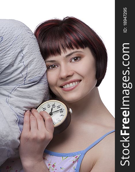 Sleepy woman is holding alarm clock at seven o'clock in the morning. Photo of a young girl waking up in the early morning..