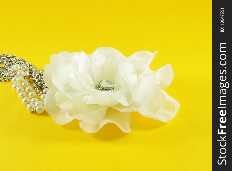 Closeup of fabric flower with pearls over yellow background
