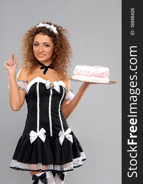 Beautiful waitress with a cake on a tray. Gray background