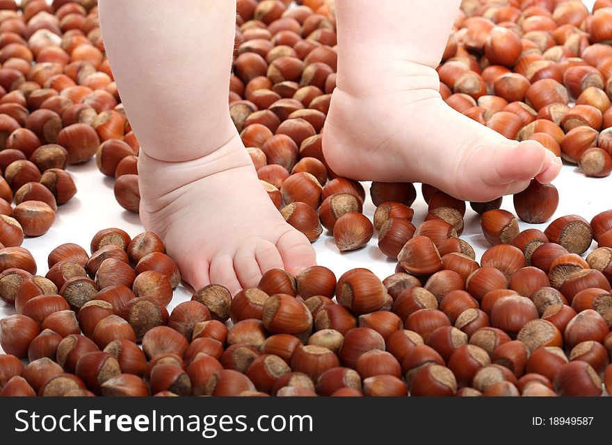 Baby's feets on scaterring nuts. Baby's feets on scaterring nuts