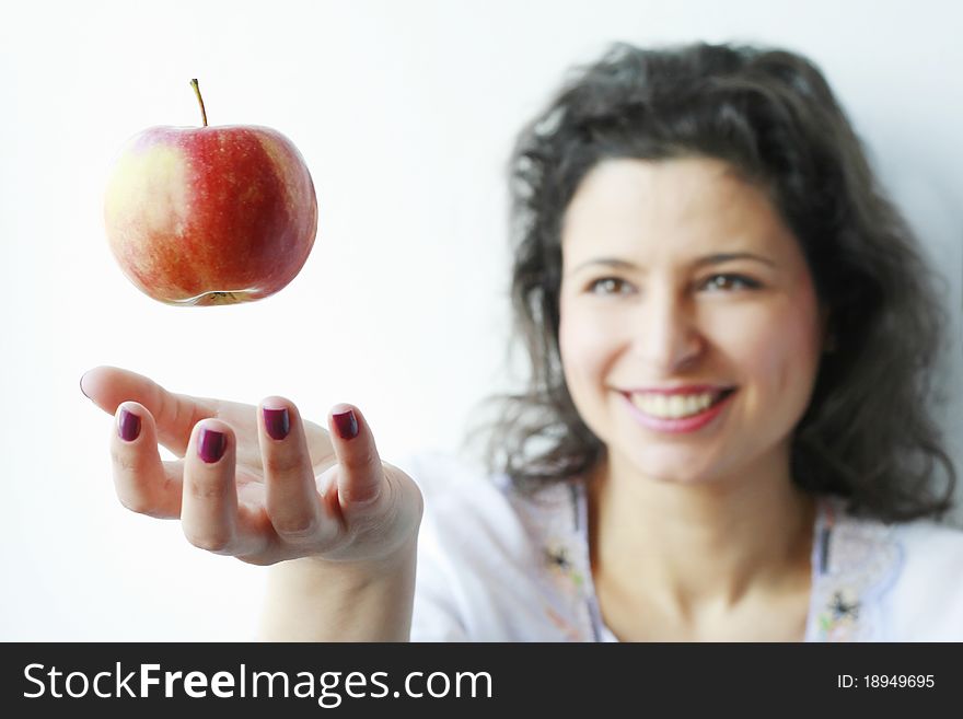 Woman smiling at a red apple floating in the air trying to catch it. Woman smiling at a red apple floating in the air trying to catch it