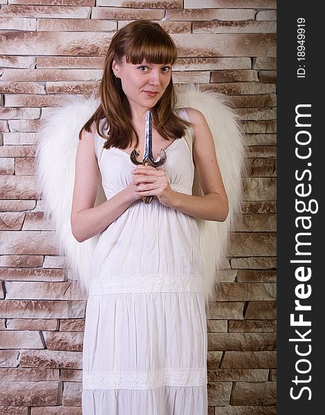 Angel girl with knife on brick wall background. Angel girl with knife on brick wall background