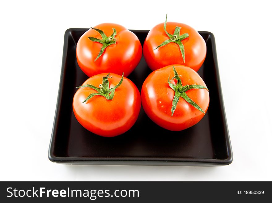 Picture of four tomatoes on a black plate