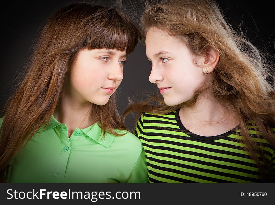 Portrait of two young beautiful girls in studio a dark background