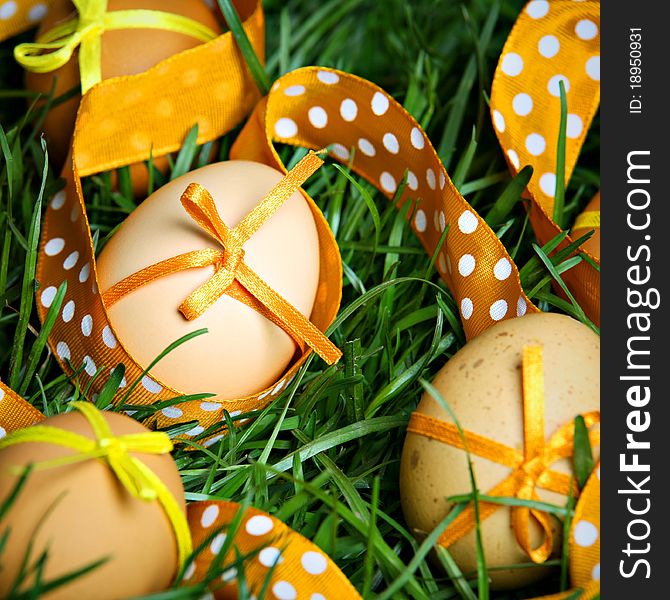 Easter eggs with orange ribbon hidden in the grass. Easter eggs with orange ribbon hidden in the grass