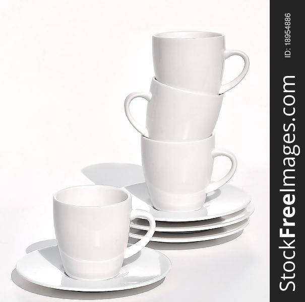 Coffee cups and saucers stacked on white background