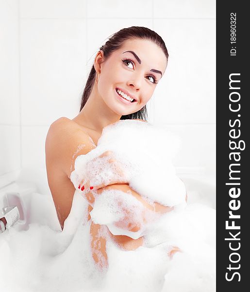 Beautiful young brunette woman taking a relaxing bath with foam. Beautiful young brunette woman taking a relaxing bath with foam