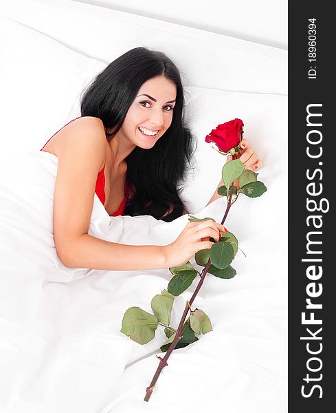 Beautiful brunette woman wakes up and finds a rose in her bed. Beautiful brunette woman wakes up and finds a rose in her bed