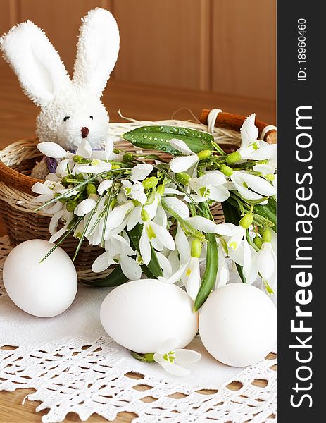 Toy rabbit, eggs and snowdrops in a basket