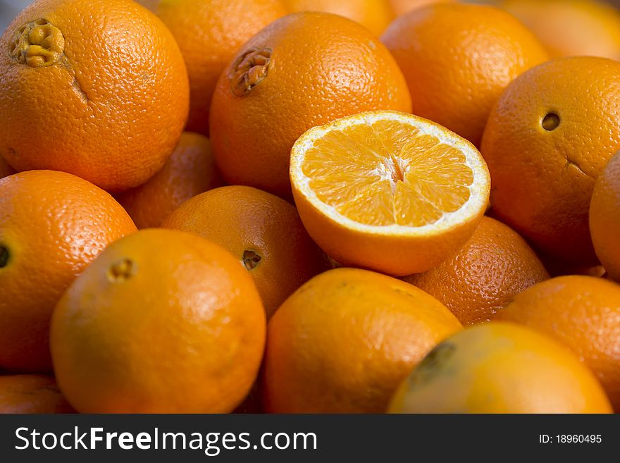 Close up on a half-cut orange sitting on a big pile. Close up on a half-cut orange sitting on a big pile.