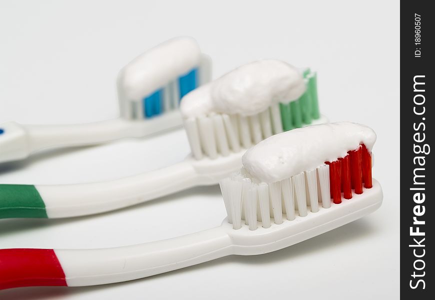 Three colorful toothbrushes with toothpaste