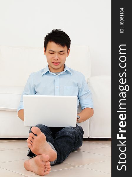 A man sitting on the floor using a laptop. A man sitting on the floor using a laptop