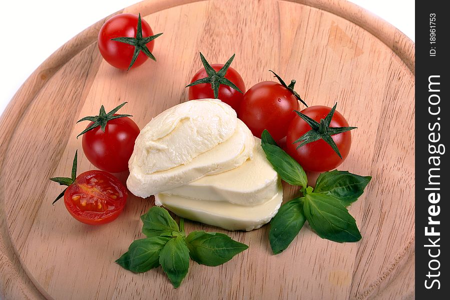 Mozzarella cherry tomatoes basil on a wooden board