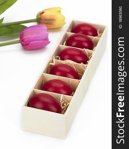 Red eggs in a wooden box decorated with tulips. Red eggs in a wooden box decorated with tulips