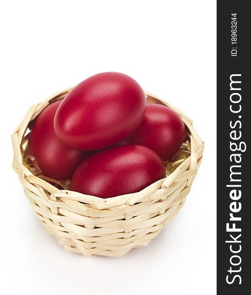 Red eggs in a wicked basket isolated on a white background. Red eggs in a wicked basket isolated on a white background