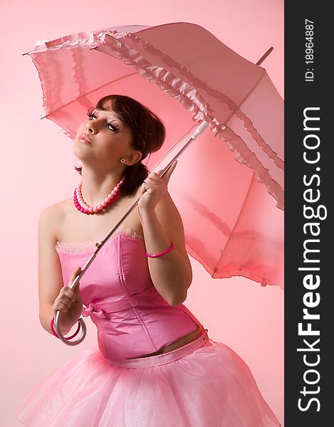 The girl with an umbrella on a pink background
