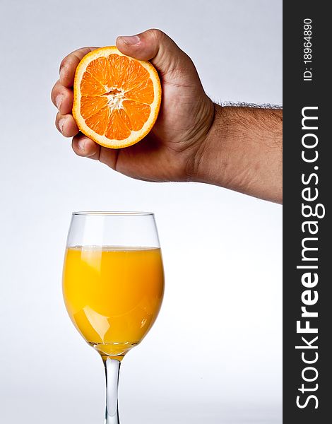 Squeezing orange into a glass of juice. Squeezing orange into a glass of juice