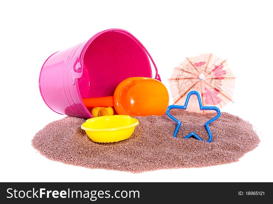 Plastic beach toys and an iron bucket on a beach sand isolated over white background. Plastic beach toys and an iron bucket on a beach sand isolated over white background