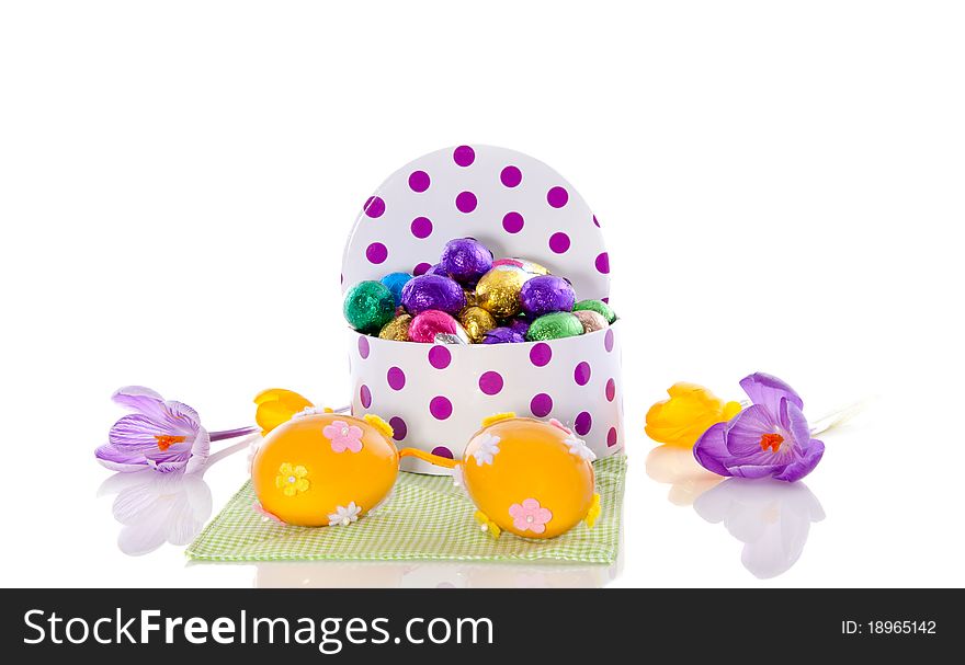 Edible and decorative easter eggs in a box on a napkin with spring crocus flowers isolated over white background. Edible and decorative easter eggs in a box on a napkin with spring crocus flowers isolated over white background