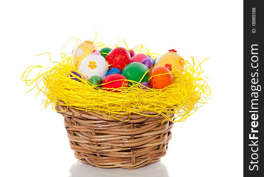 Cheerful easter eggs in straw in a wicker basket isolated over white background. Cheerful easter eggs in straw in a wicker basket isolated over white background