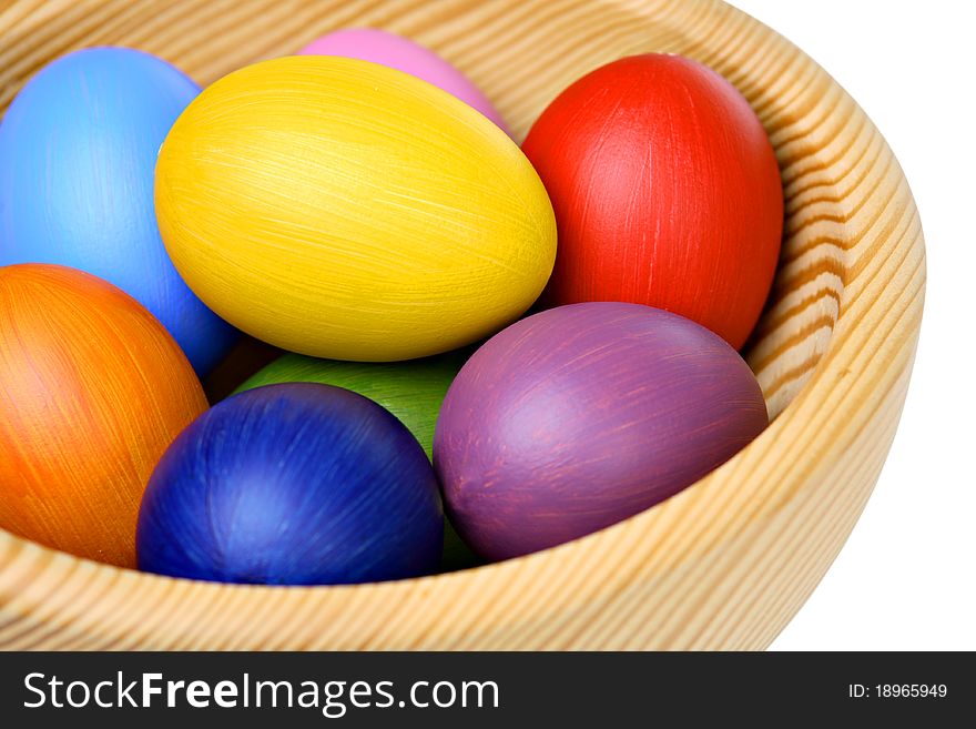 Colorful Easter eggs in wooden bowl, isolated on white