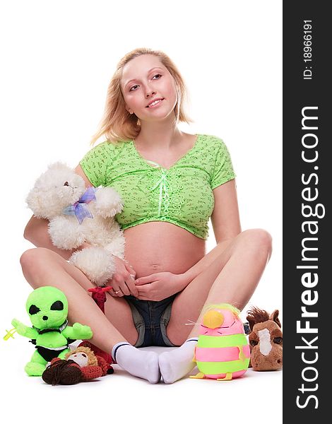 Cute pregnant girl, seated, surrounded by toys